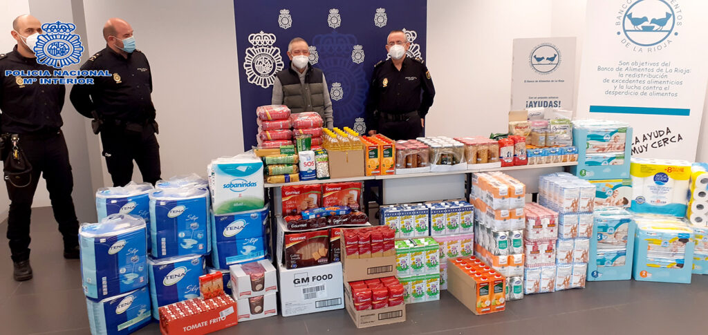 Dos agentes de policía y una persona posan junto a alimentos.