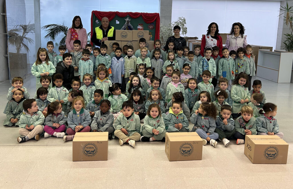 Escolares posan con cajas de alimentos durante una actividad solidaria.
